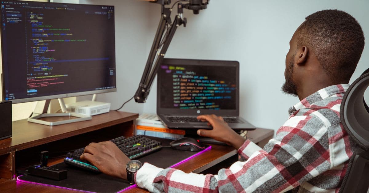 A developer working at a desk with code on two screens in a Nairobi office
