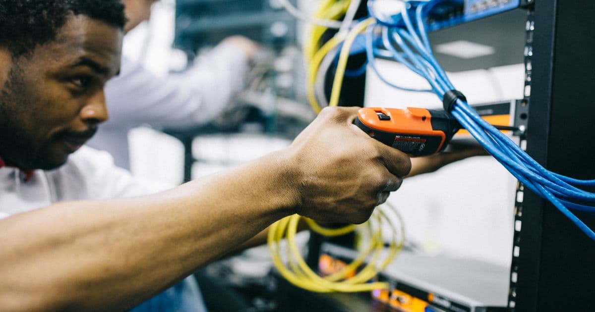 An IT technician working with network cables in a server rack