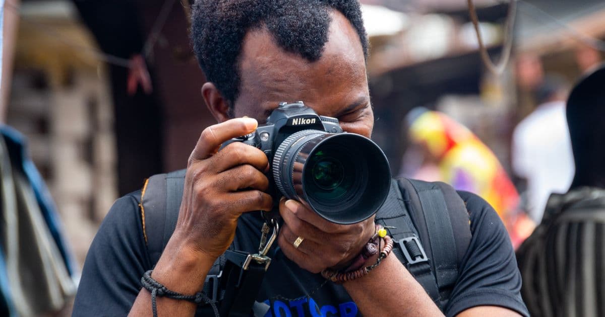 A photographer taking a picture with a DSLR camera in a busy market